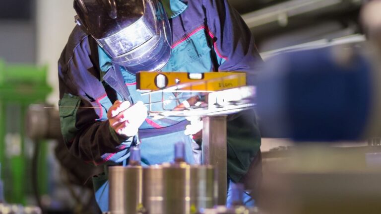 Metal Worker with Welding Mask Looking at a Fabrication